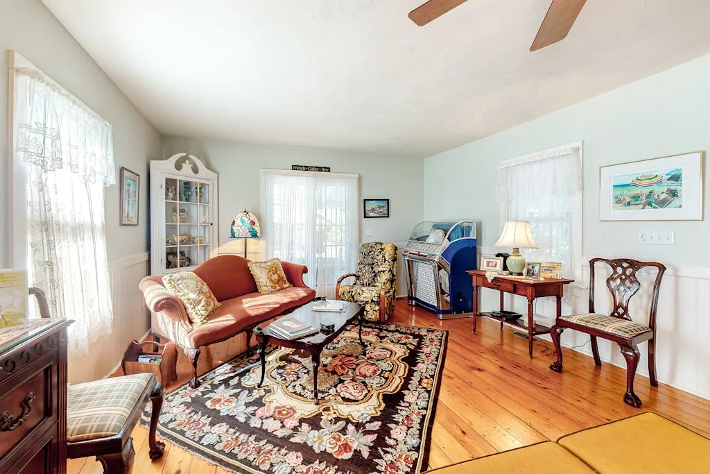 A living room with seating arranged around a floral rug and coffee table.