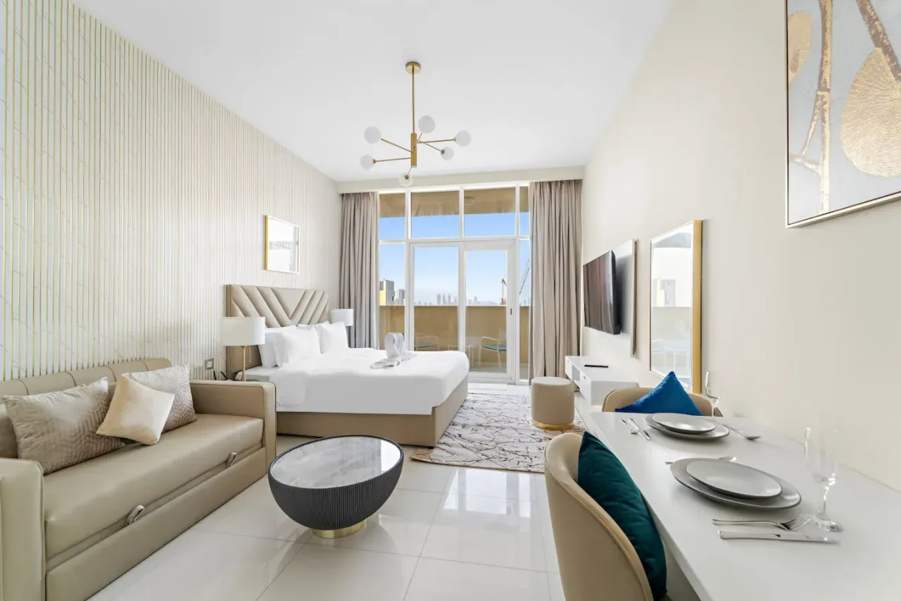 A bright bedroom with a bed, seating area, and large windows.