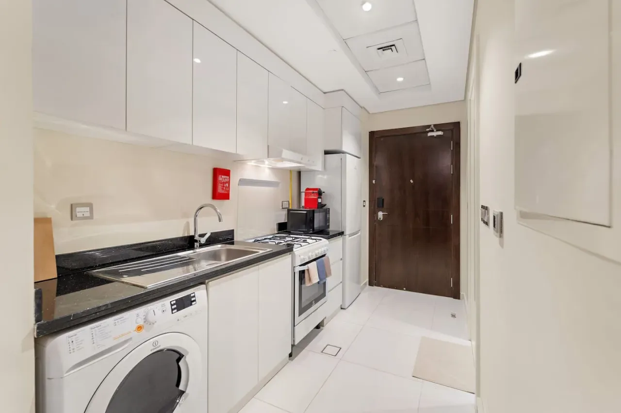 A compact kitchen with white cabinetry, a countertop, and built-in appliances.