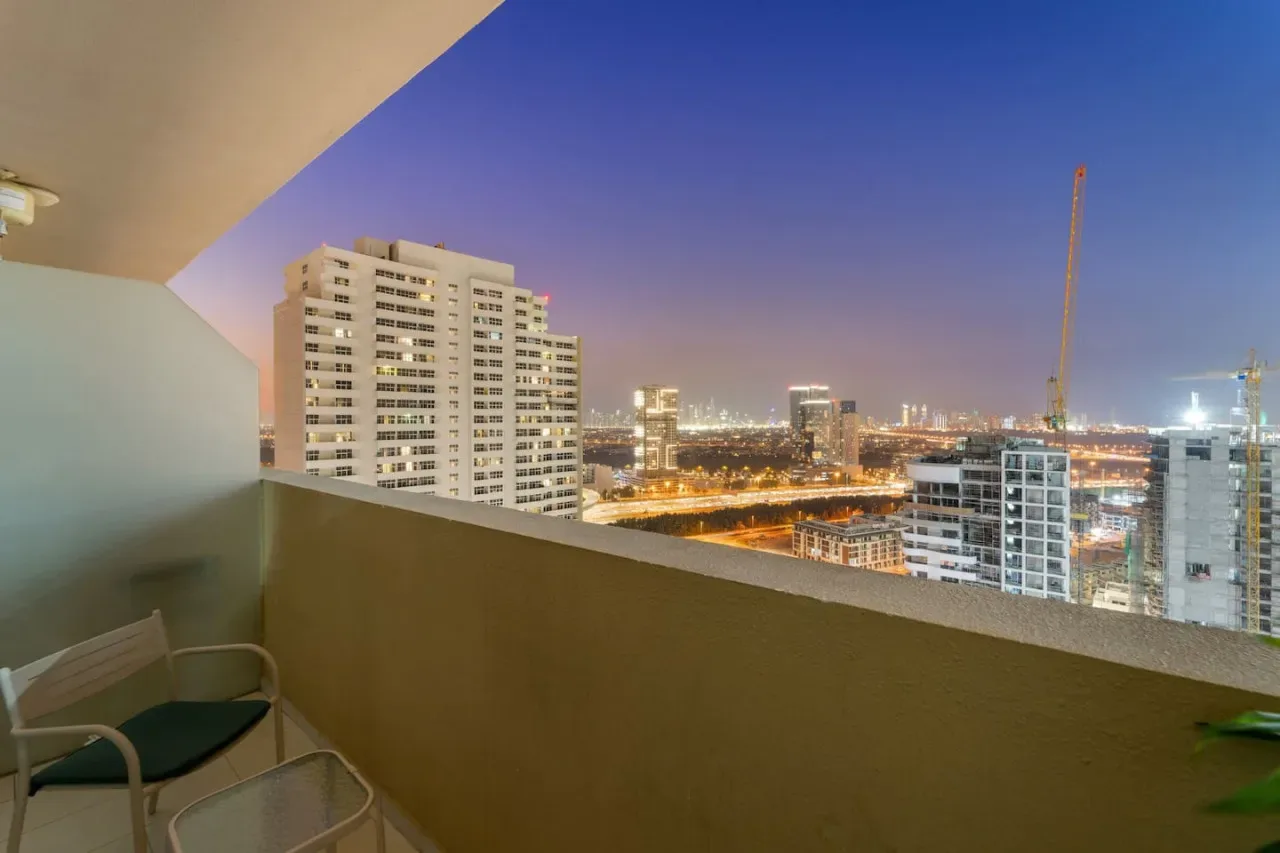 A balcony overlooks illuminated city buildings at dusk.