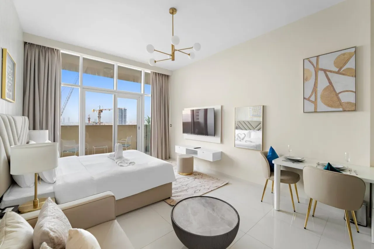 A bright bedroom with a bed, large windows, and a small desk.