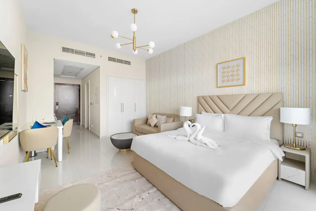 A bright bedroom with a large bed, bedside tables, and a small dining area.
