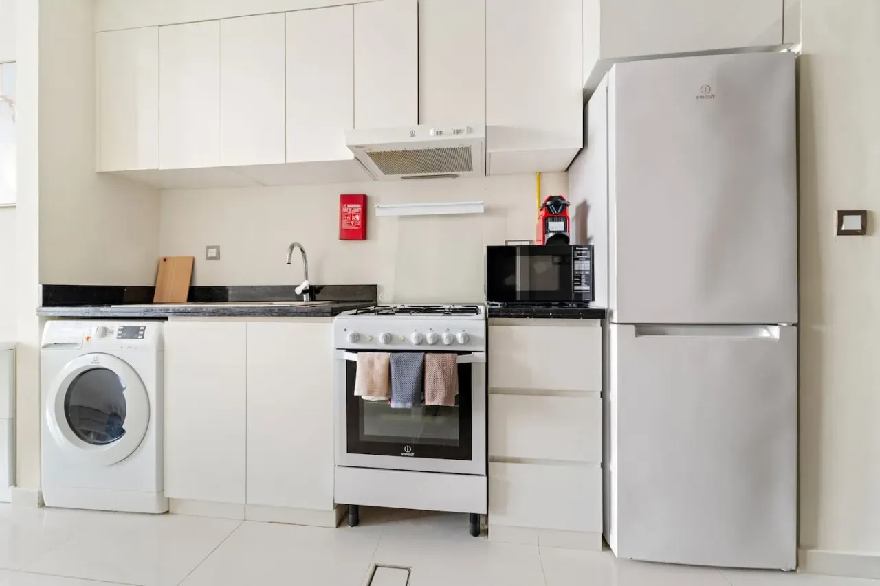 A bright kitchen with white cabinets, a stove, and a refrigerator.
