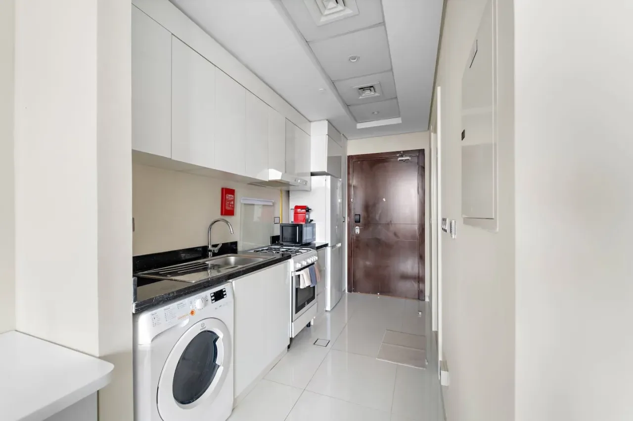 A narrow kitchen with white cabinets, a countertop, and appliances.