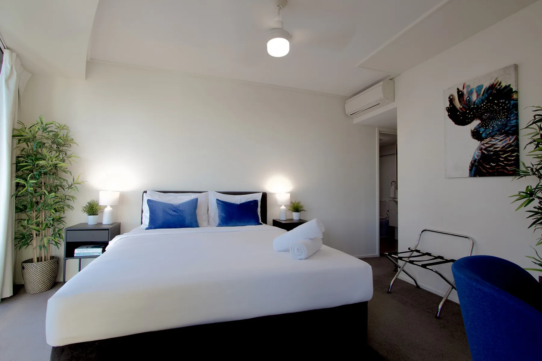 A bedroom with a neatly made bed and blue accent pillows.