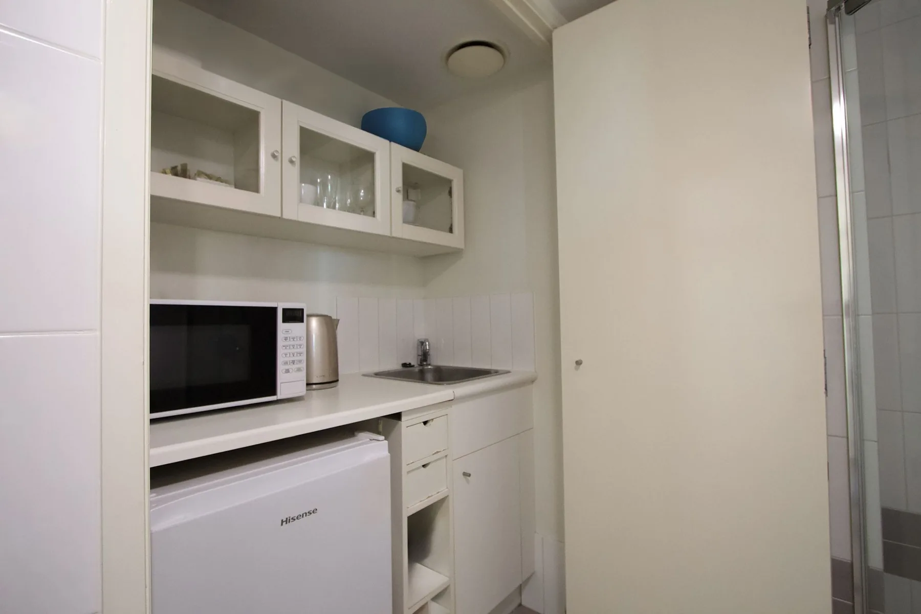 A compact kitchenette with a microwave, sink, and under-counter refrigerator.