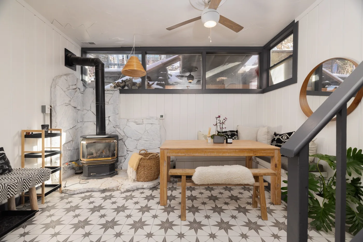 Comedor con una mesa de madera, suelo estampado y una estufa de leña.