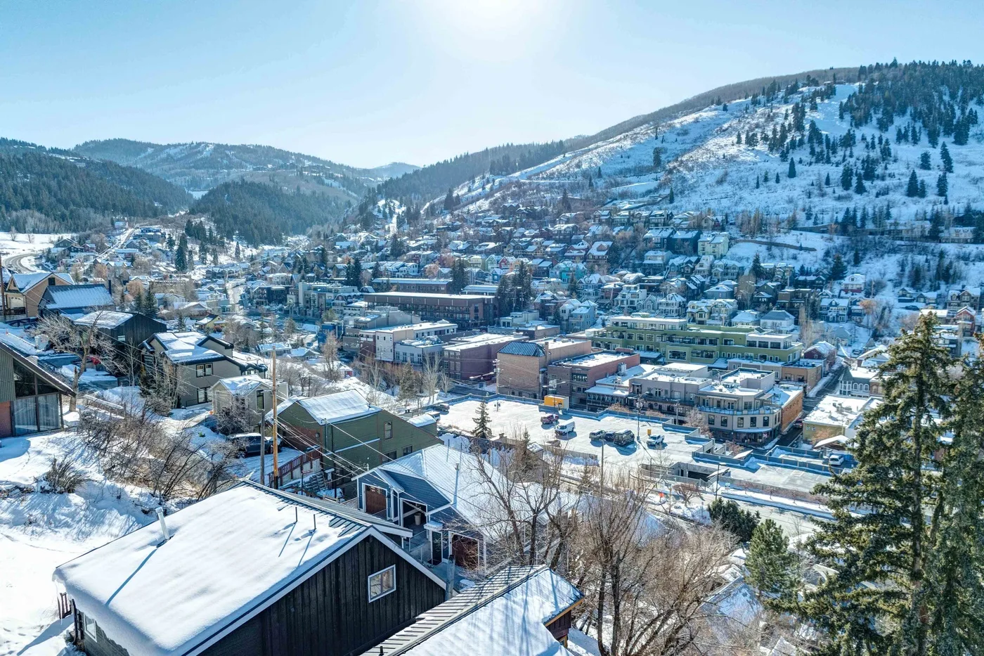 Un pueblo de montaña cubierto de nieve se extiende por un valle bajo laderas boscosas.