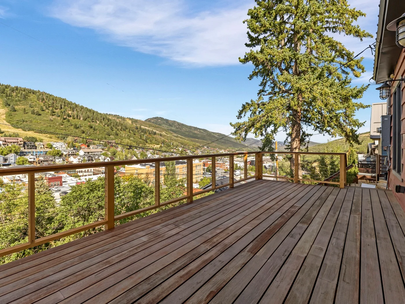 Una amplia terraza de madera ofrece vistas a un valle arbolado y una ladera.