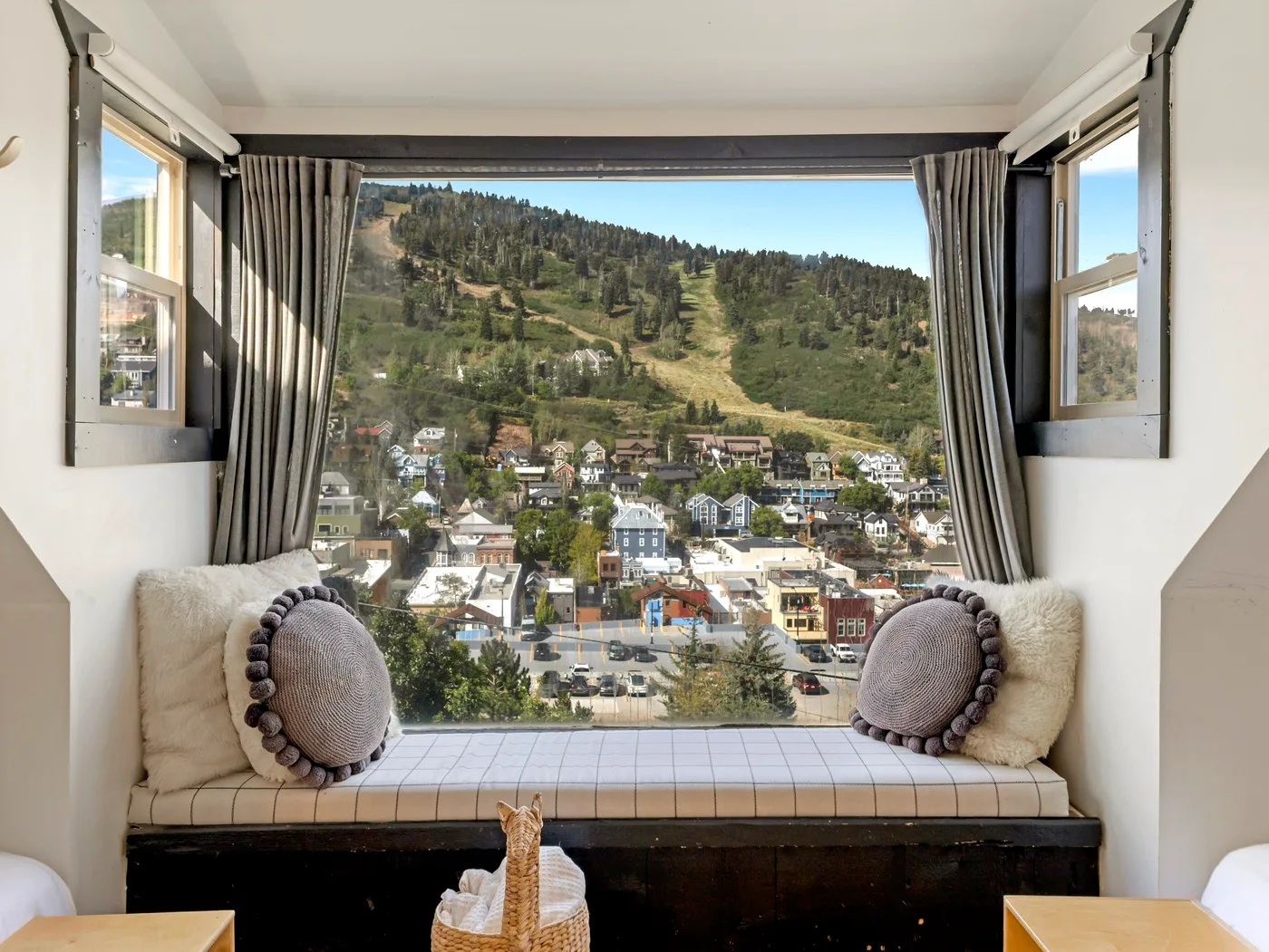 Una zona de asientos junto a la ventana da a un pueblo en la ladera y colinas verdes.