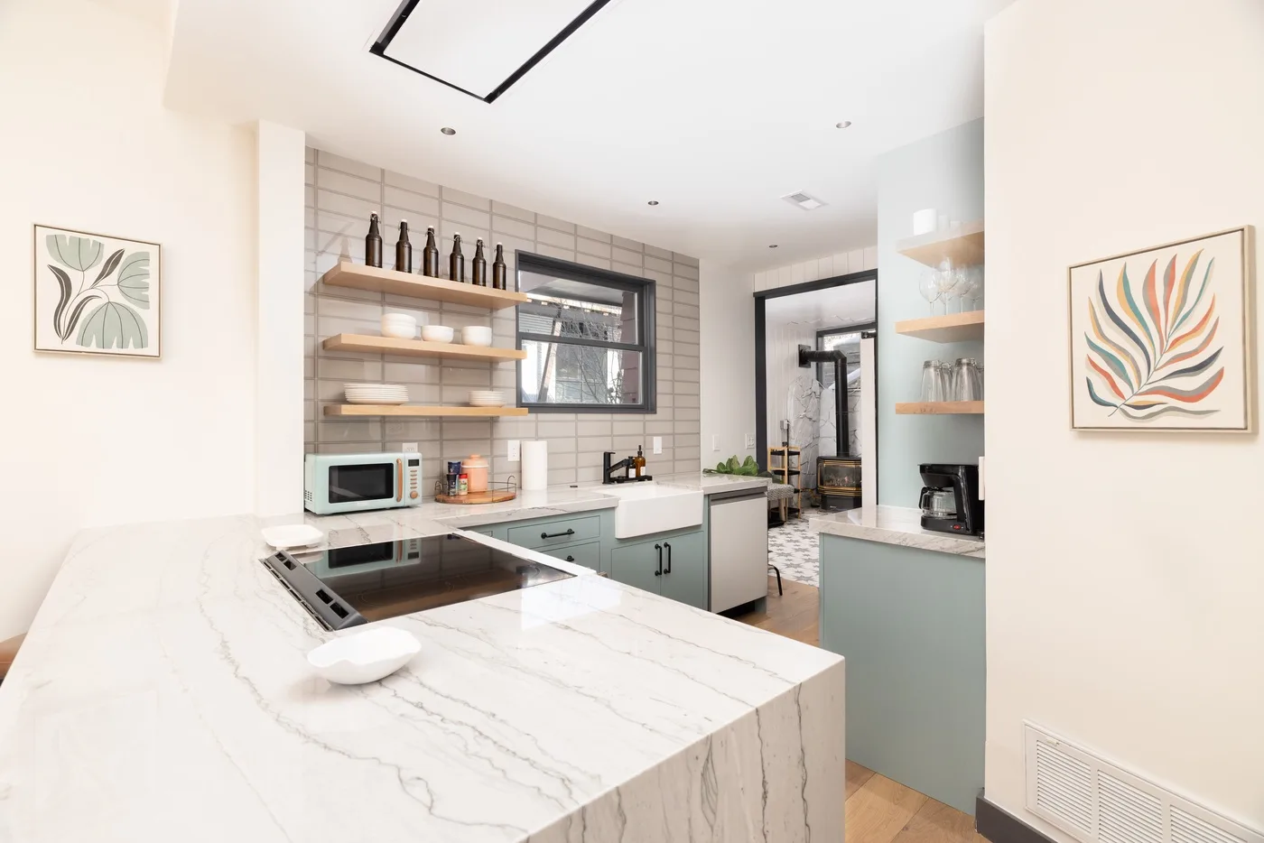 Una cocina moderna y luminosa con una isla de mármol y estantes abiertos.