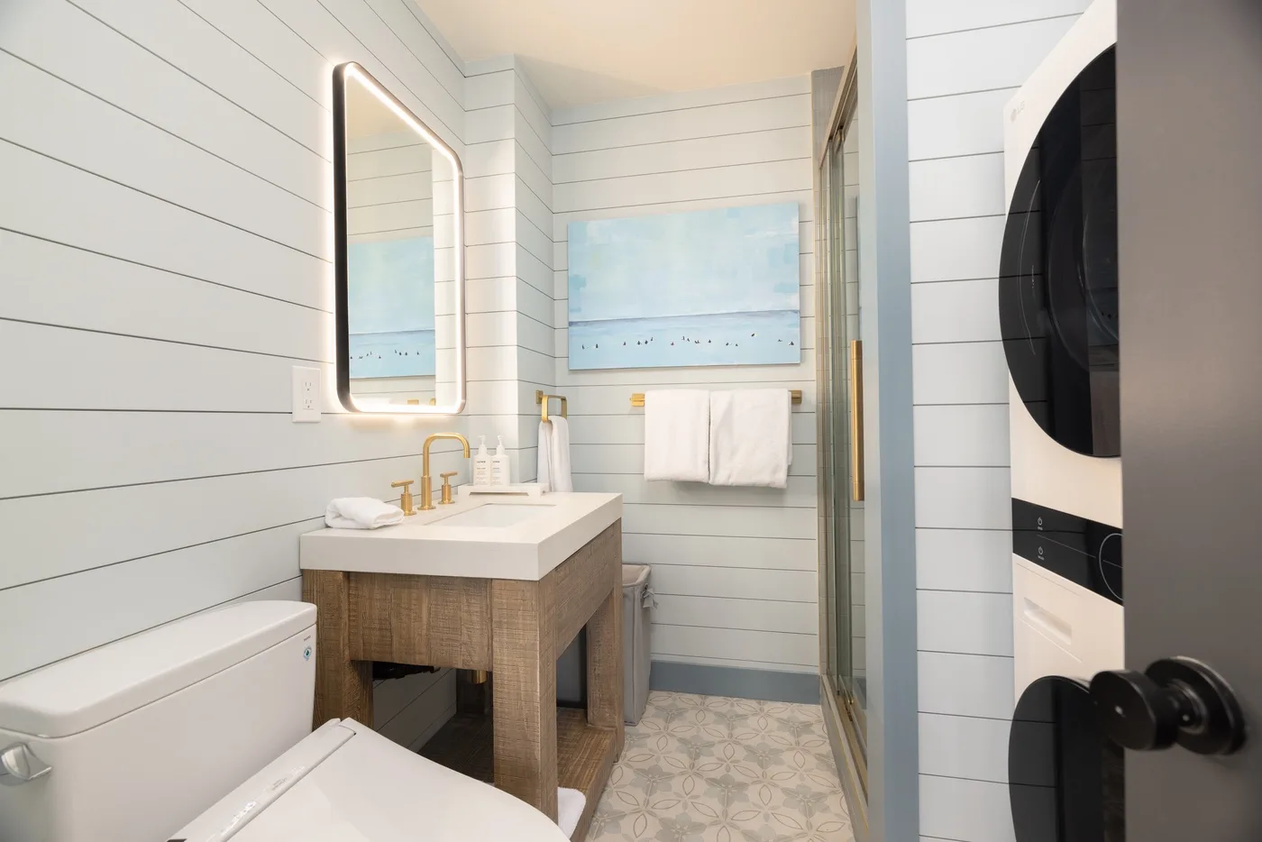 Un baño luminoso con lavabo, espejo y ducha.