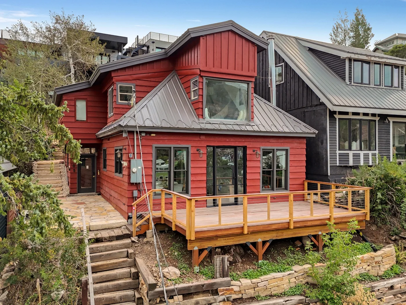 Una casa roja con una terraza elevada de madera y escalones de piedra delante.