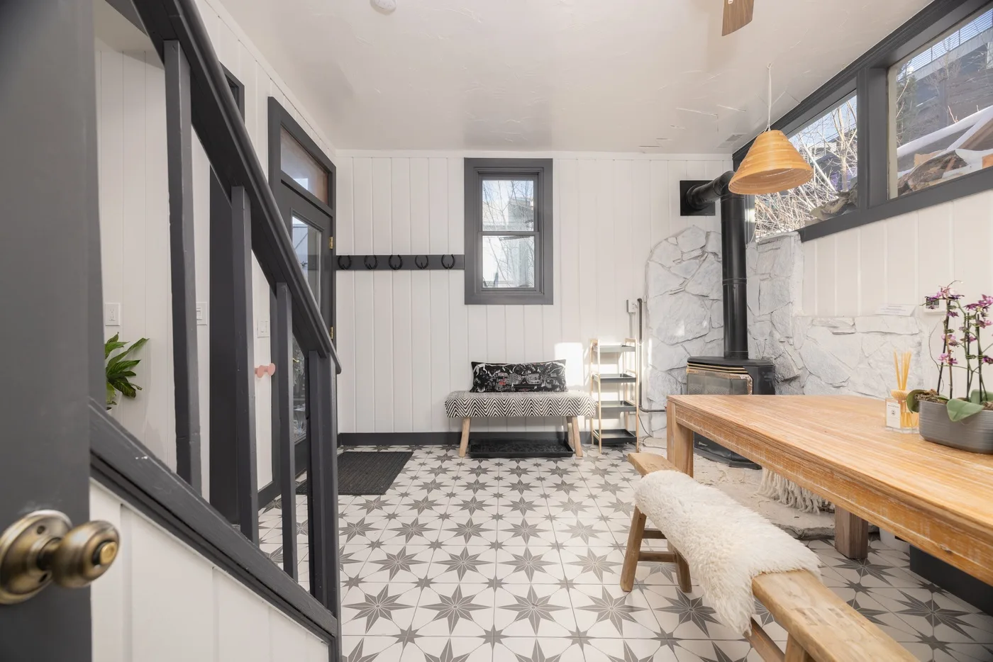 Un comedor luminoso con una mesa larga de madera y suelo de baldosas estampadas.