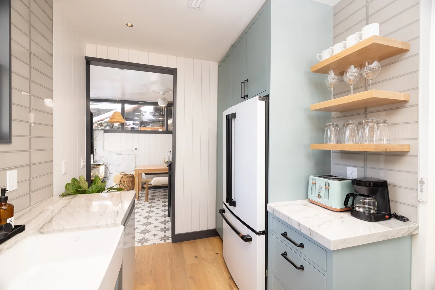 Una cocina luminosa con refrigerador, encimera y estantes abiertos.