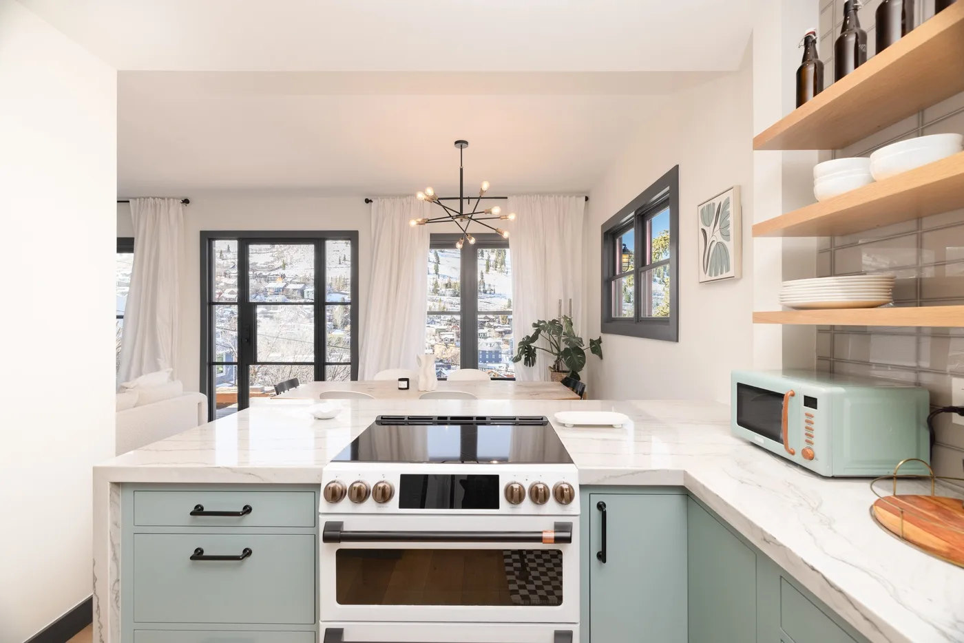 Una cocina luminosa con isla central, estufa y estantes abiertos.