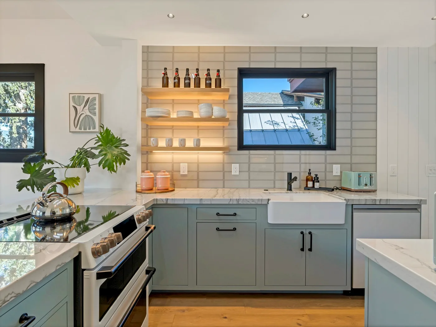 Una cocina luminosa con gabinetes grises, un fregadero central y una ventana sobre la encimera.