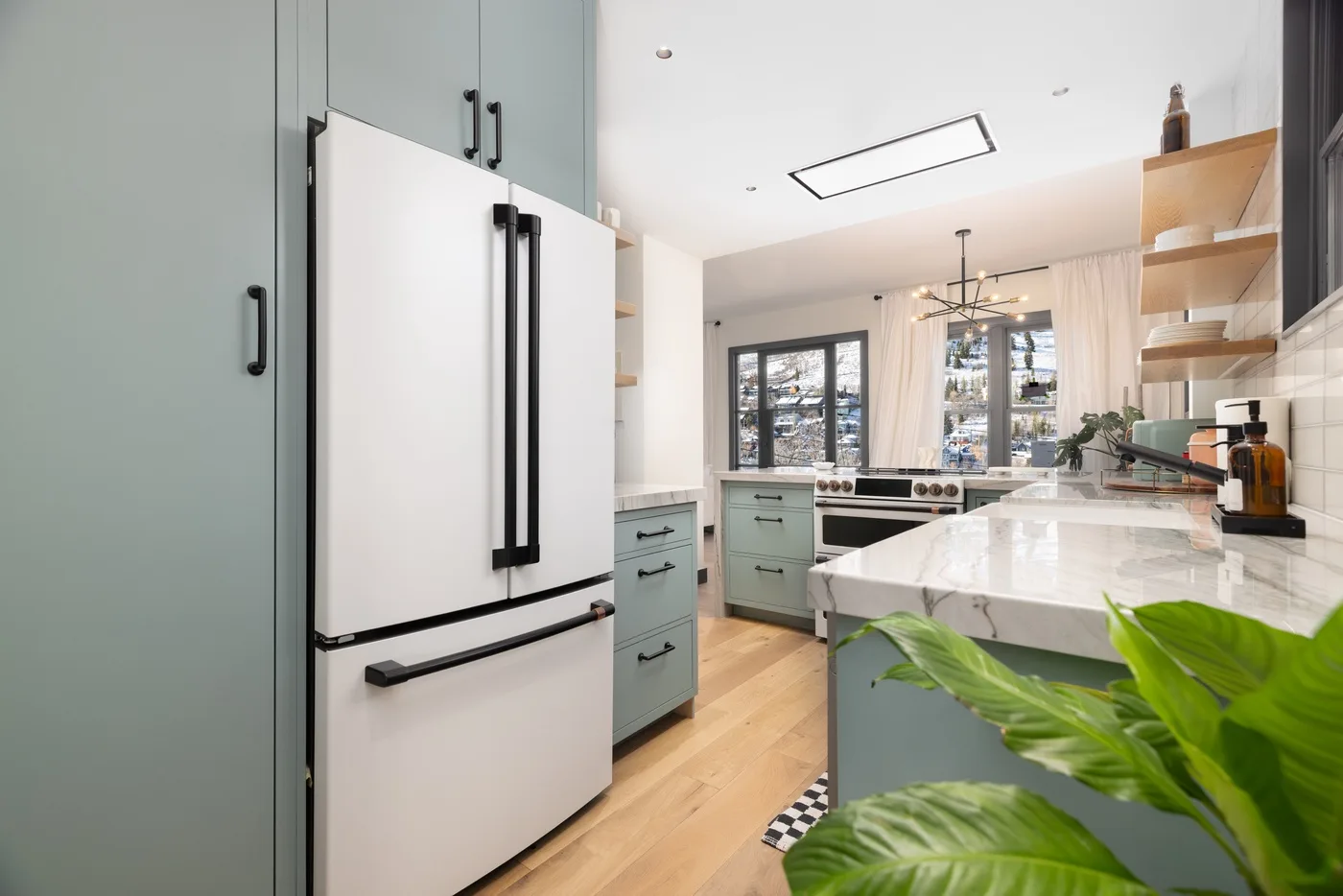 Una cocina luminosa con gabinetes claros, una isla amplia y ventanas con vista a los árboles.