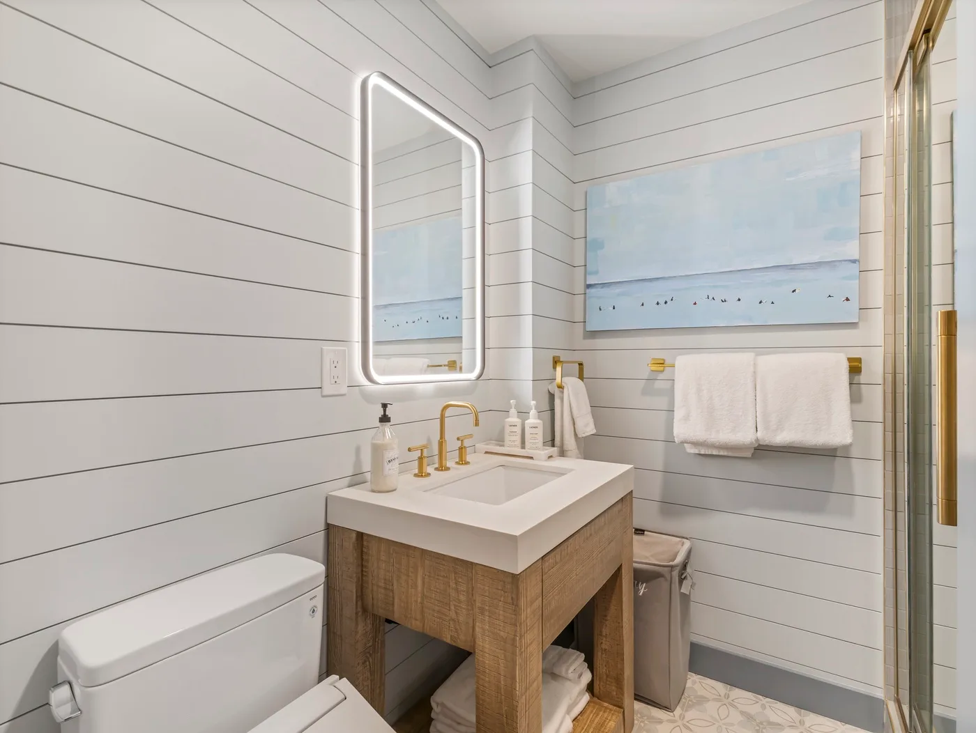 Un baño luminoso con tocador de madera, espejo de pared y toallas.