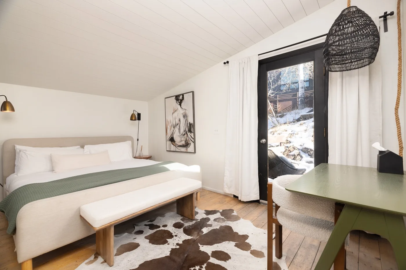 Un dormitorio con una cama, un escritorio y una ventana con vistas a un paisaje nevado.