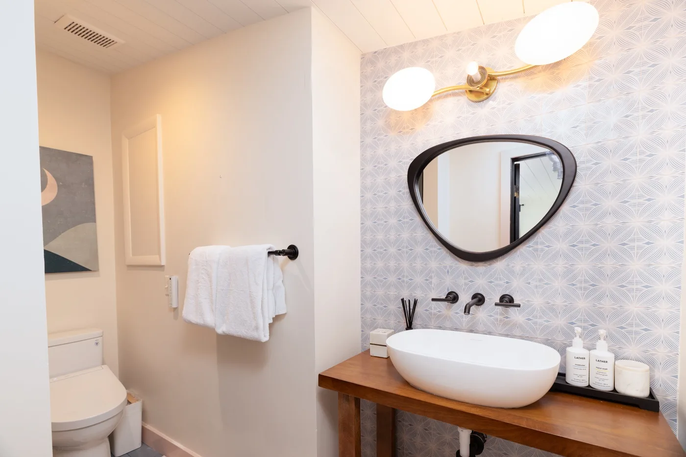 Un baño luminoso con lavabo blanco, espejo de pared y toalla.