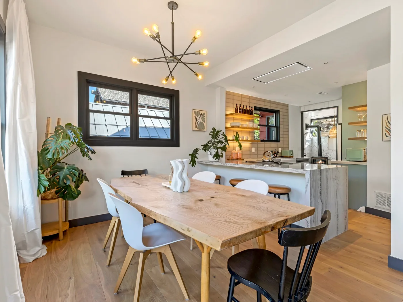 Comedor con una mesa de madera y una cocina abierta al fondo.