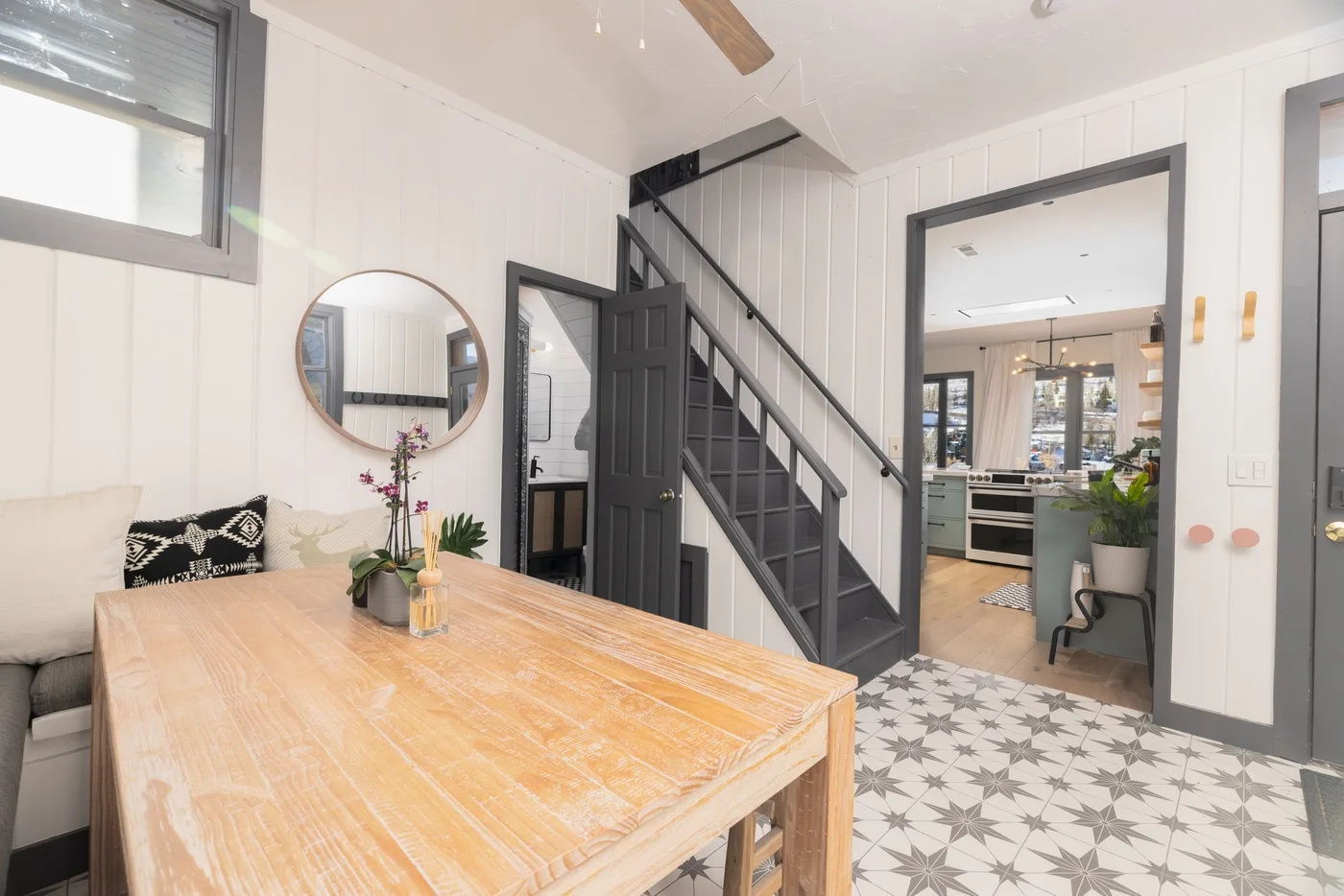 Comedor con una mesa de madera junto a una escalera y una cocina abierta.