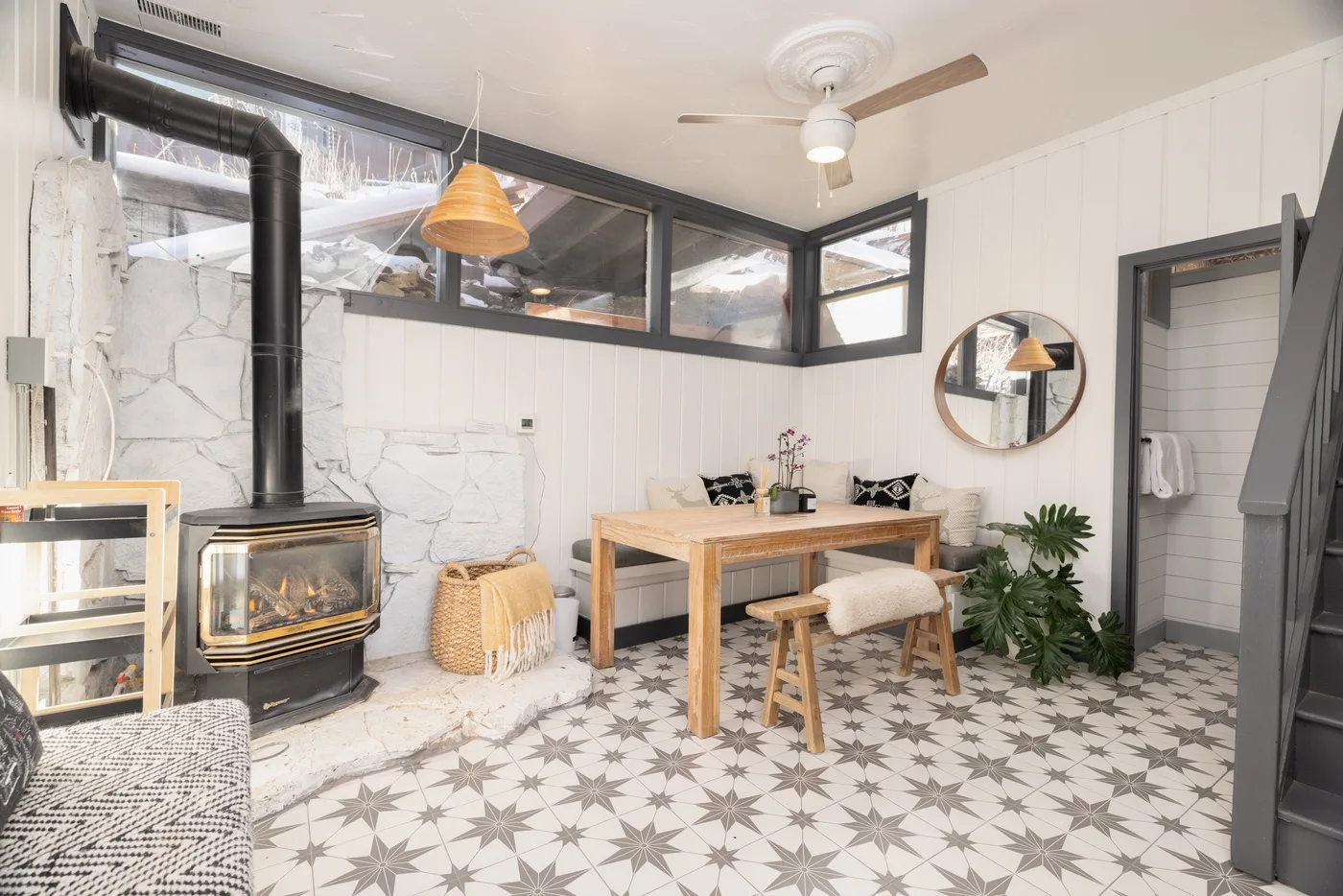 Un comedor luminoso con una mesa de madera, suelo de baldosas estampadas y chimenea.