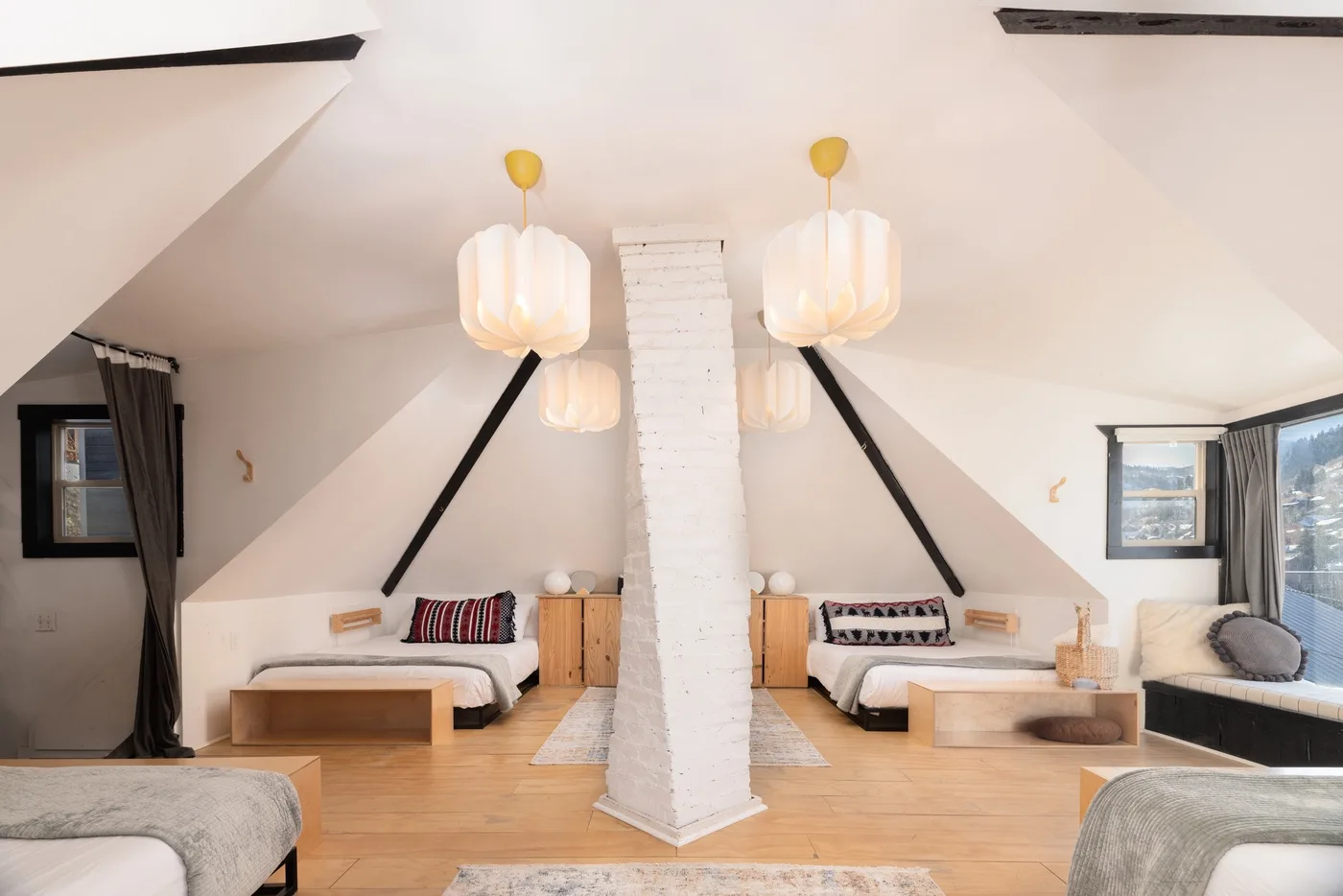 Un dormitorio abuhardillado luminoso con dos camas bajo un techo inclinado.