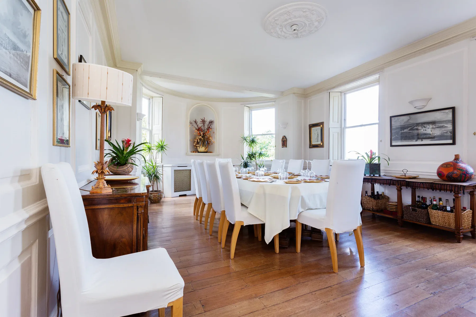Un comedor luminoso con una mesa puesta y asientos blancos.