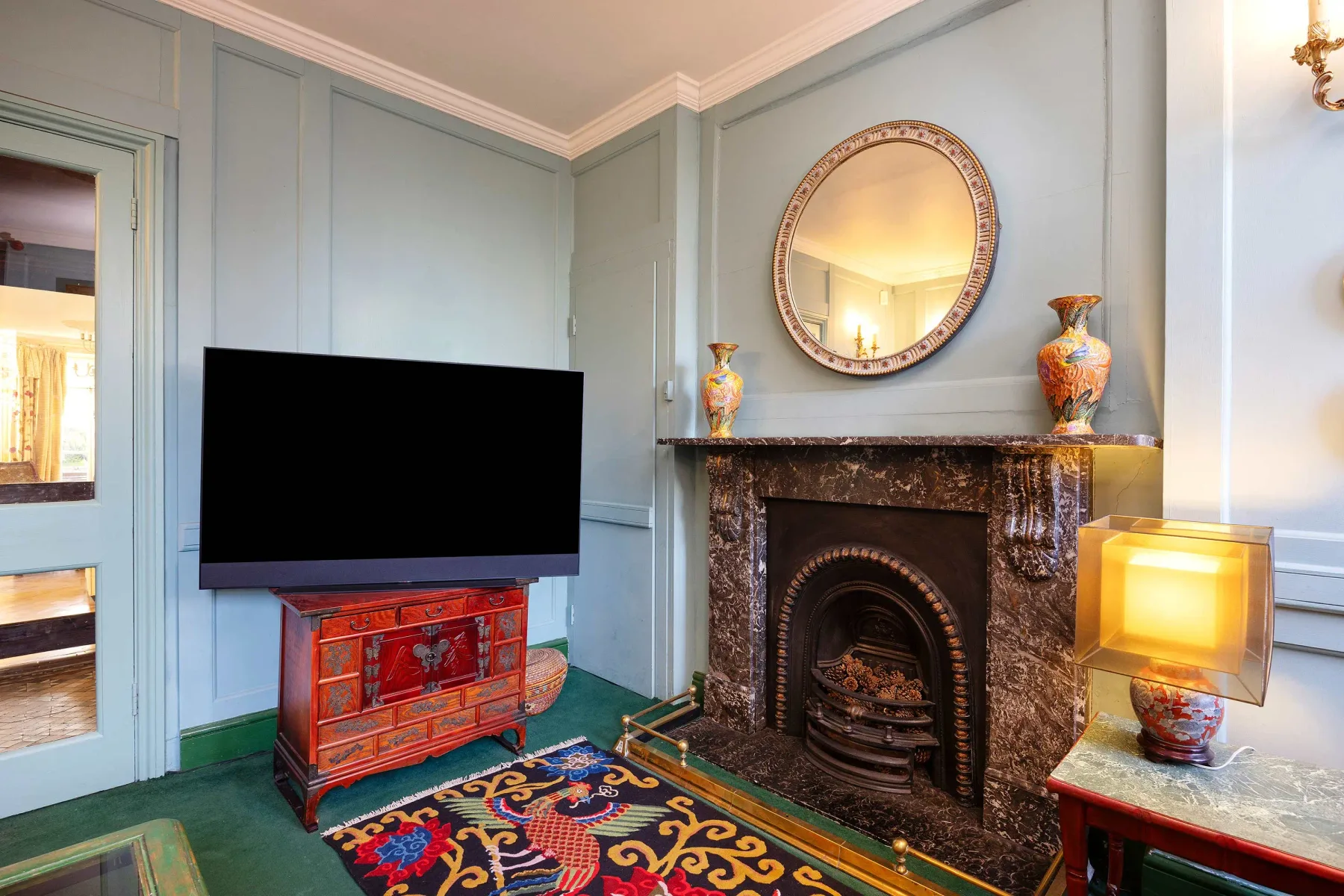 Una sala de estar con televisor, chimenea y una alfombra colorida.