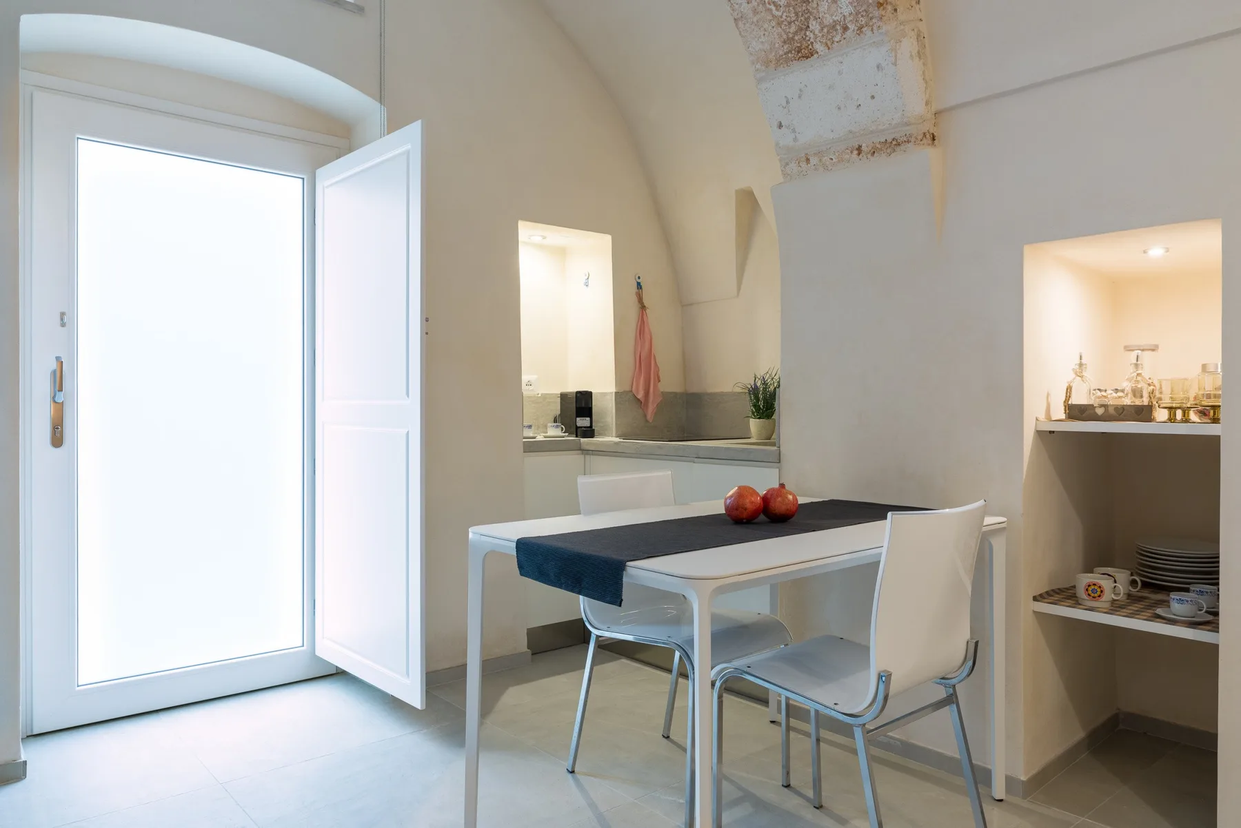 Un comedor con mesa y sillas está junto a estanterías empotradas de cocina.