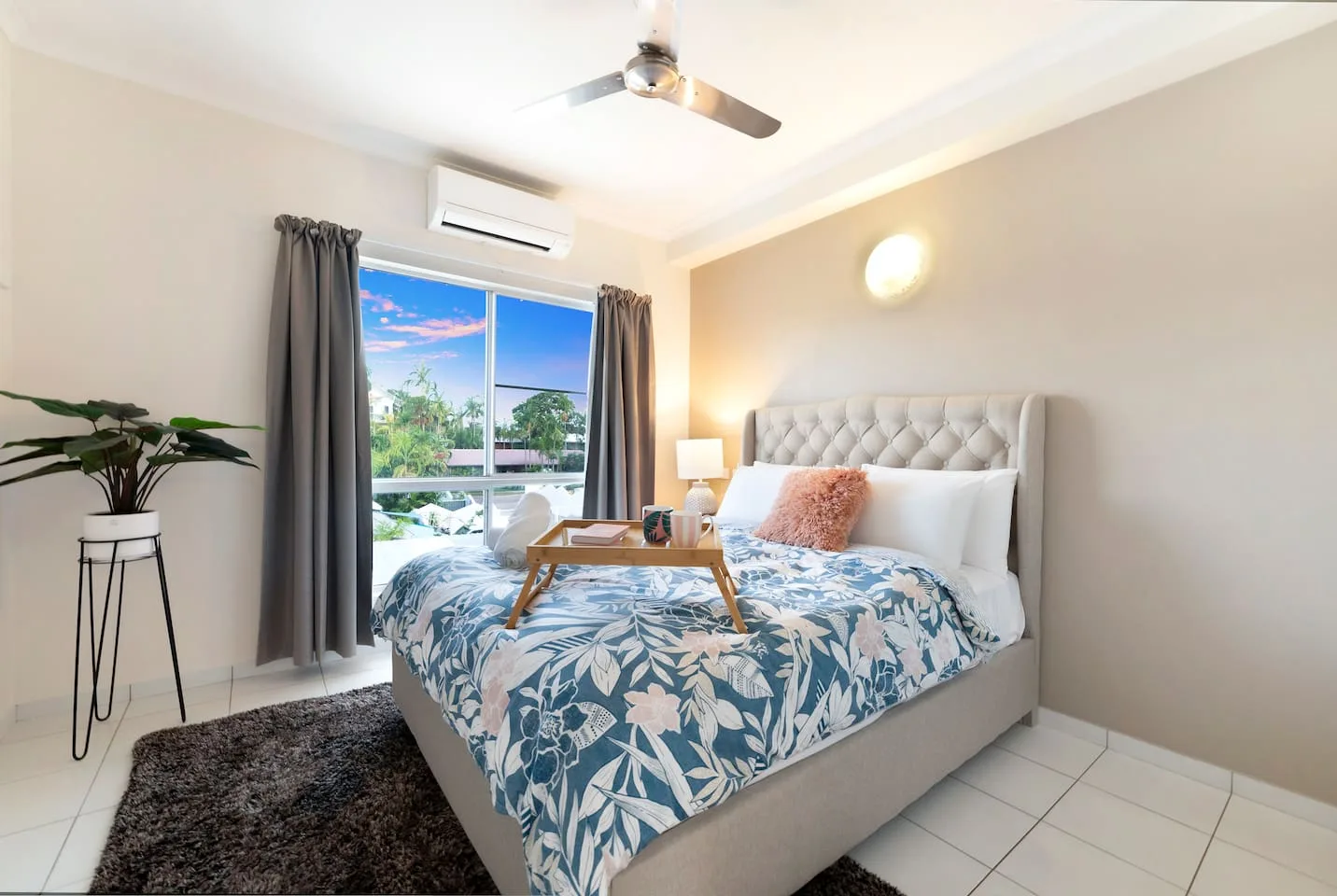 Un dormitorio con una cama cubierta con ropa de cama estampada azul y blanca junto a una ventana.