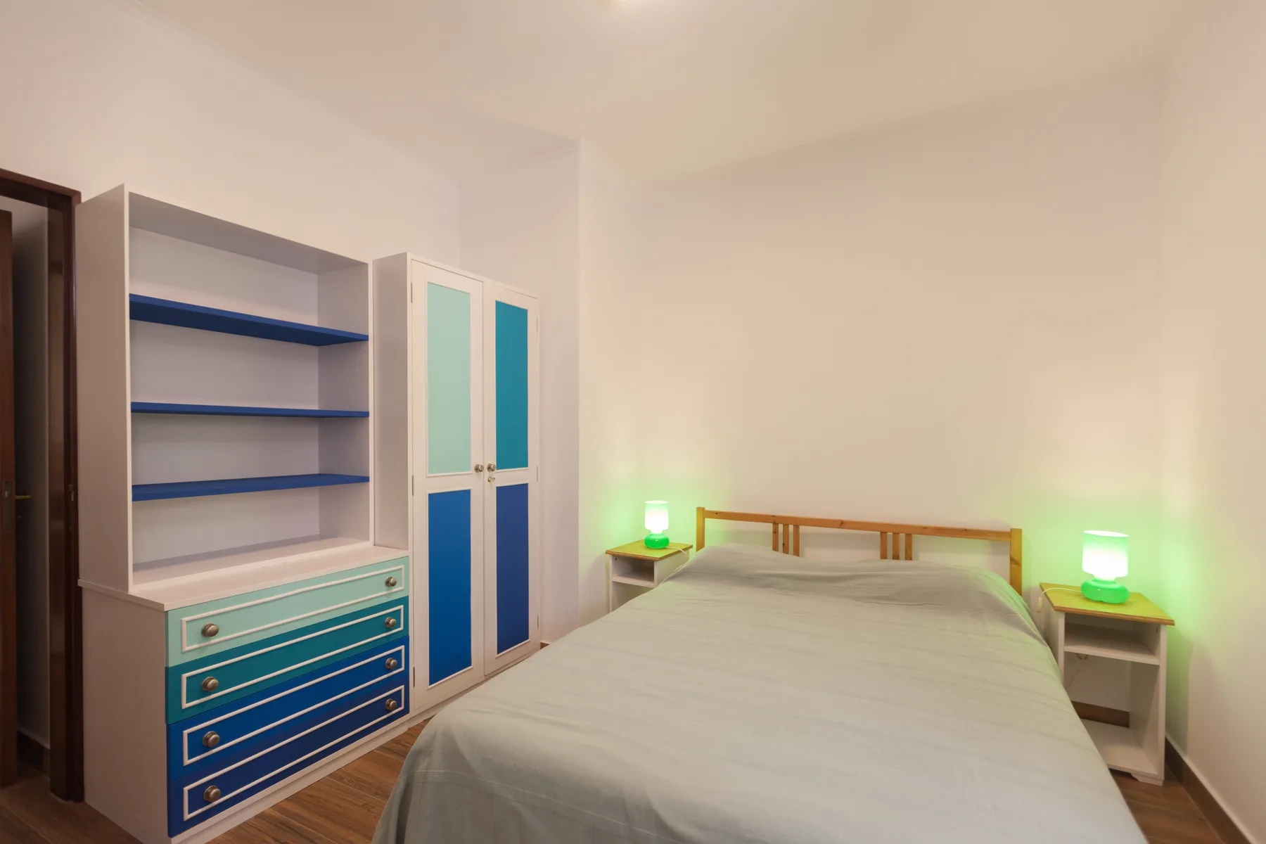 Un dormitorio con una cama junto a armarios y estantes.