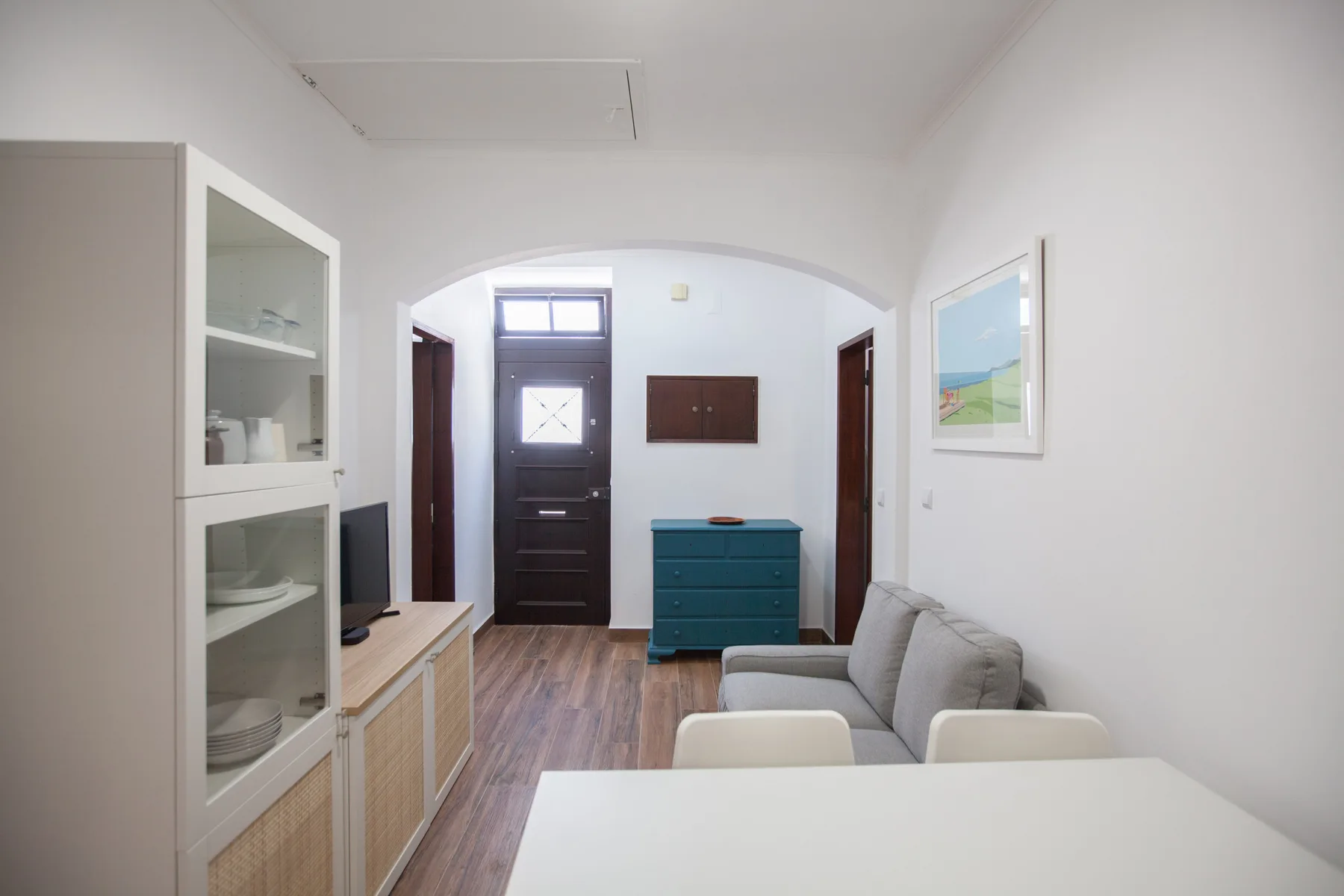 Una sala luminosa con mesa de comedor, asientos y un mueble color turquesa.