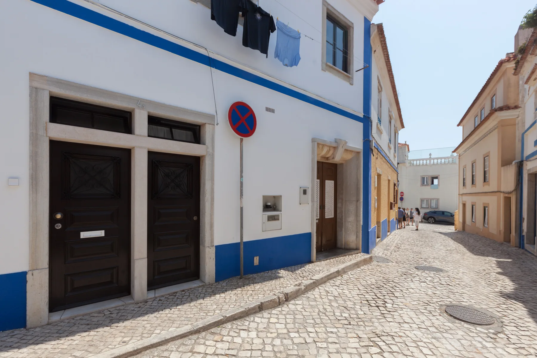 Una calle empedrada flanqueada por edificios blancos y azules.