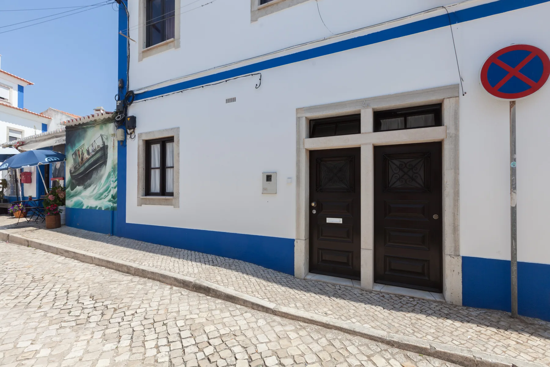 Un edificio blanco con puertas de madera oscura junto a una acera adoquinada.