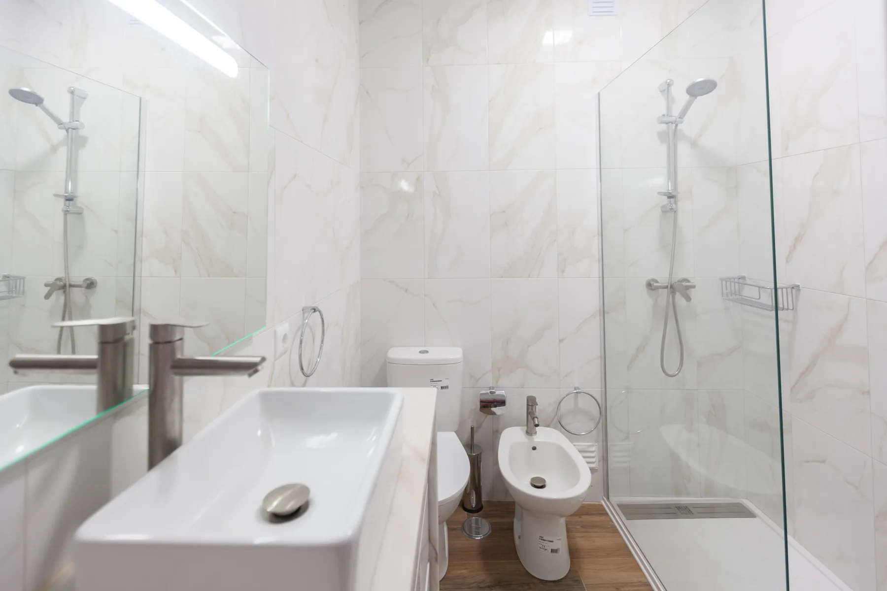 Un baño luminoso con lavabo, inodoro y mamparas de ducha de vidrio.