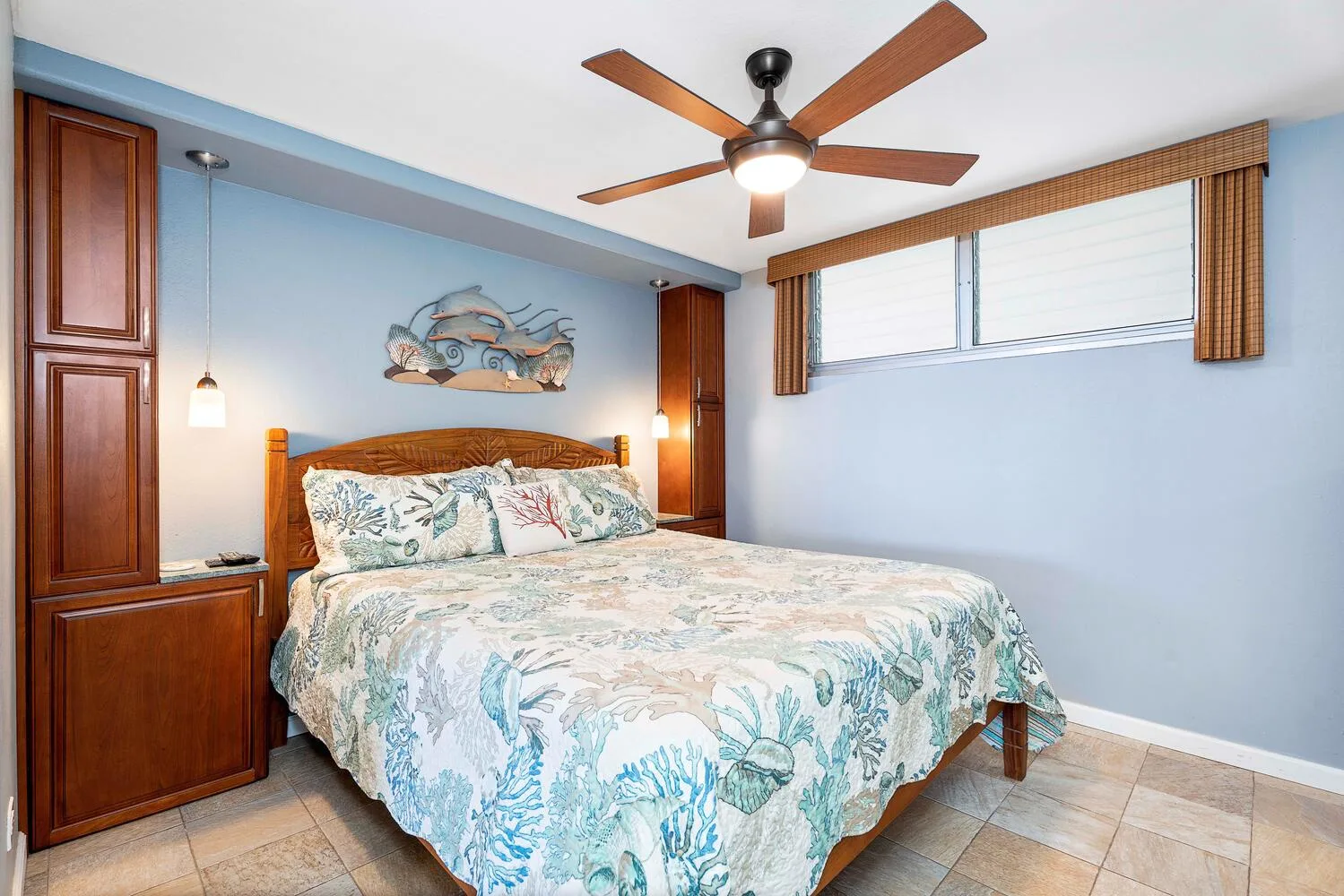 Un dormitorio con una cama, armarios de madera y un ventilador de techo.