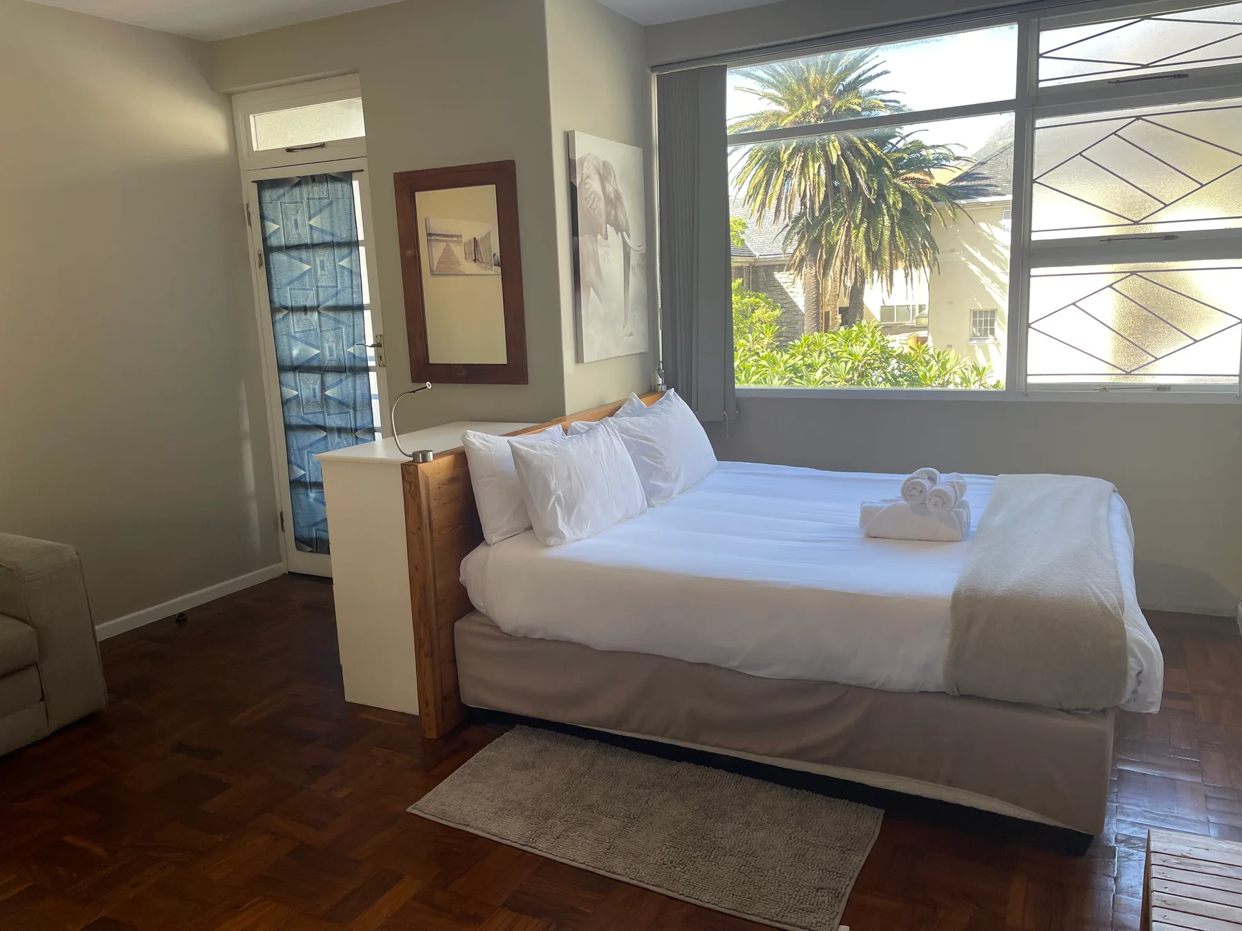 A bedroom with a neatly made bed beside a large window.