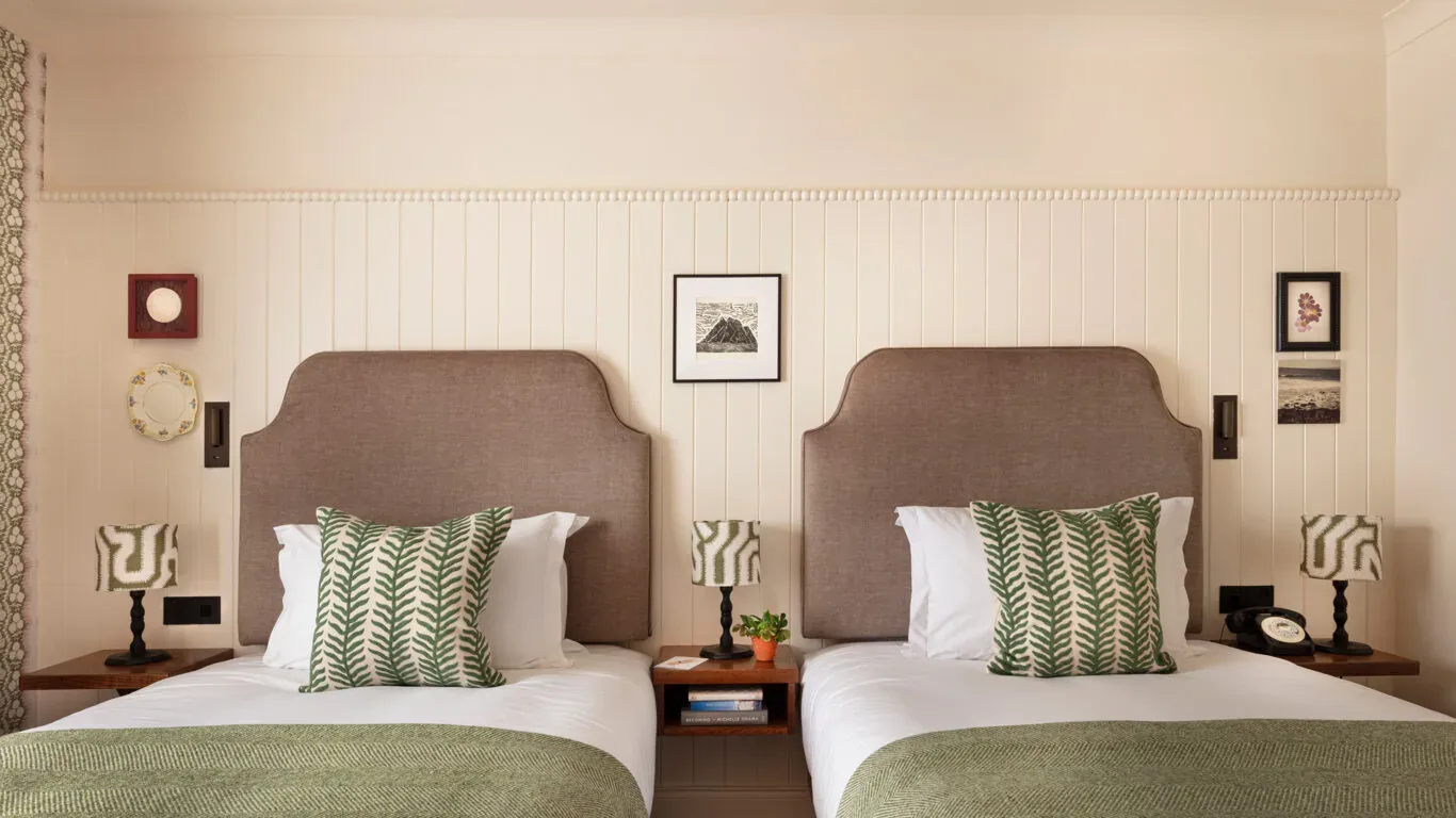 Habitación de hotel con dos camas individuales, lámparas de noche y obras de arte.