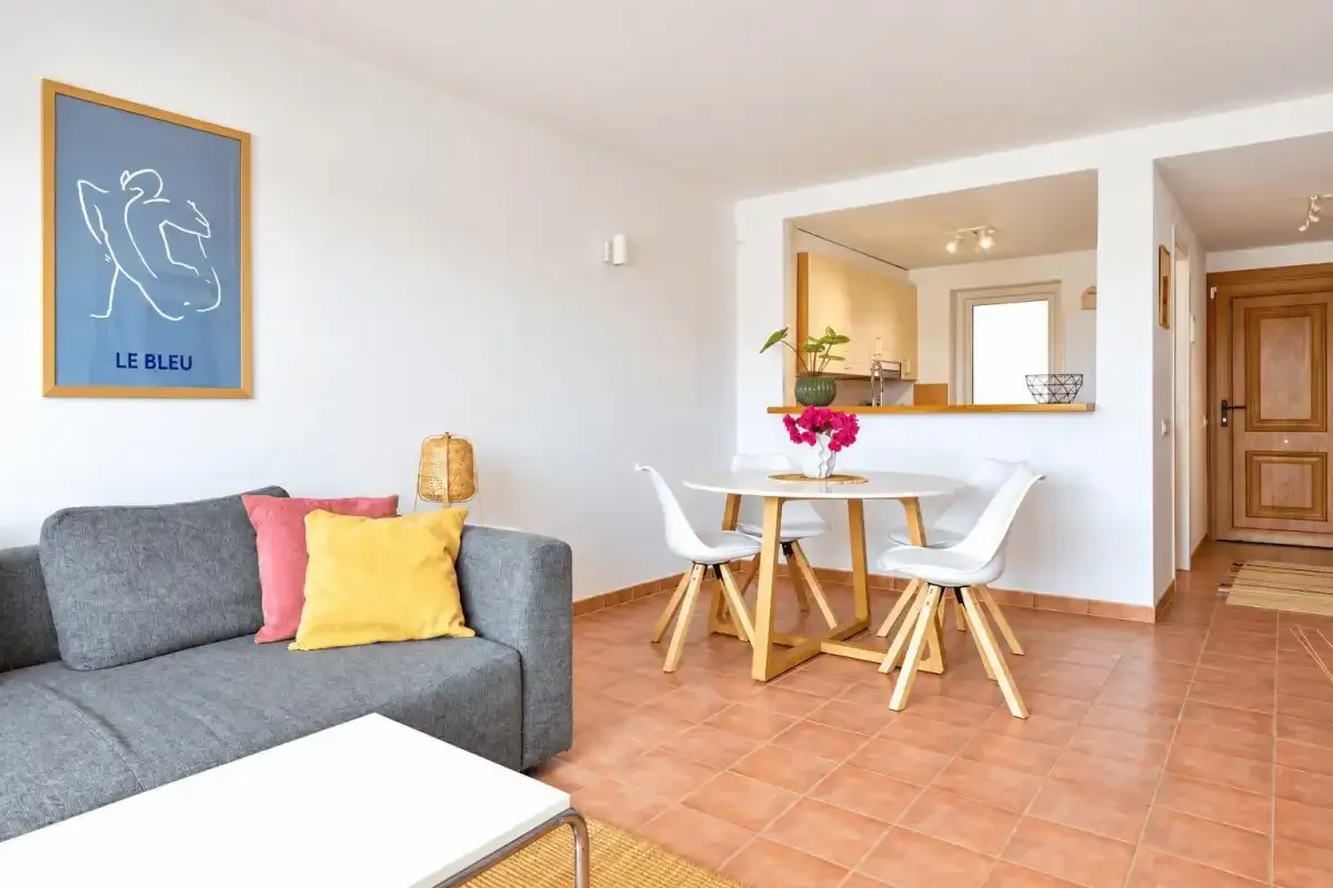 A bright living and dining area with gray seating and a table.