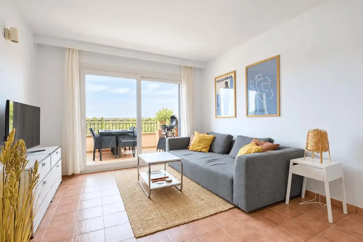 A bright living room with gray seating and sliding glass doors opening onto a balcony.
