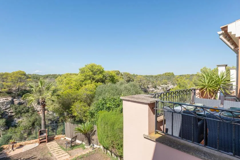 A balcony overlooks a green wooded landscape under a clear blue sky.