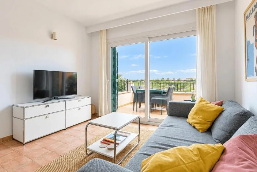 A bright living room with a gray seating area and glass doors opening onto a balcony.
