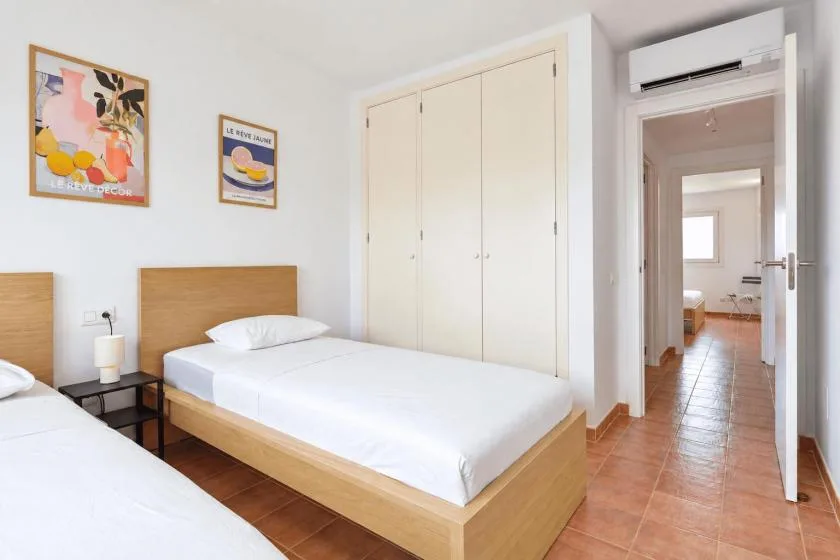 A bedroom with two beds, framed artwork, and built-in closets.