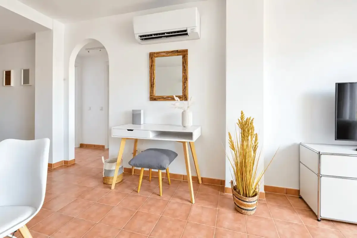 A bright room with a desk, chair, television, and potted plant.