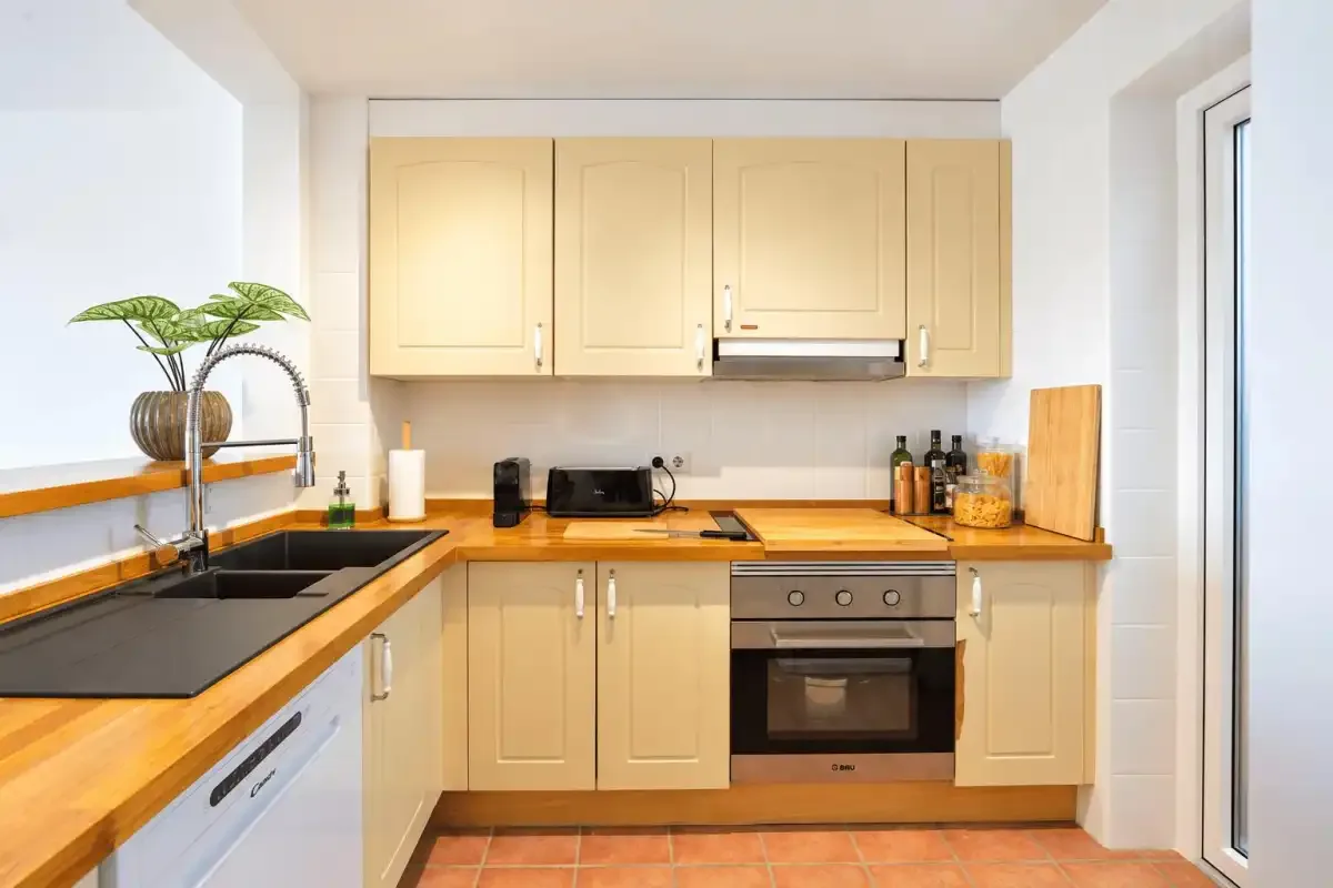 A bright kitchen with light wood cabinets, dark countertops, and a built-in oven.