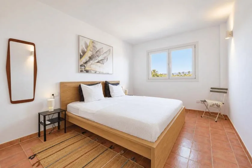 A bright bedroom with a neatly made bed and a window.