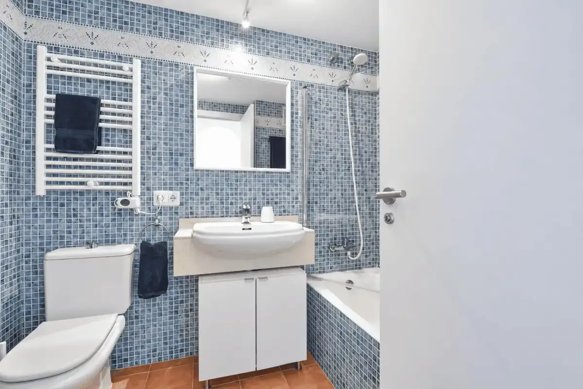 A tiled bathroom with a sink, mirror, toilet, and bathtub.